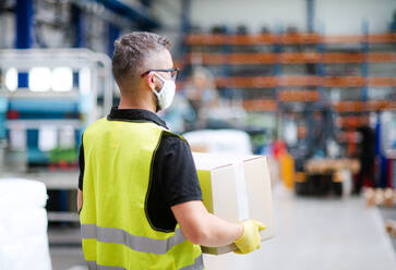 Mature man worker with protective mask working in industrial factory or warehouse. - HPIF15015