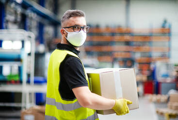 Portrait of man worker with protective mask working in industrial factory or warehouse. - HPIF15016