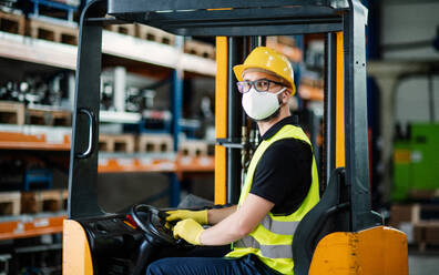 Porträt von Mann Arbeiter Gabelstaplerfahrer mit Schutzmaske arbeiten in der industriellen Fabrik oder Lager. - HPIF15019