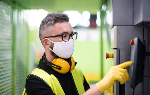 Porträt eines Arbeiters mit Schutzmaske, der in einer Fabrik oder einem Lagerhaus arbeitet. - HPIF15021