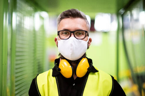Portrait Mann Arbeiter mit Schutzmaske stehend in industrieller Fabrik oder Lager. - HPIF15022