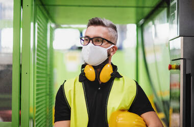 Portrait Mann Arbeiter mit Schutzmaske stehend in industrieller Fabrik oder Lager. - HPIF15023