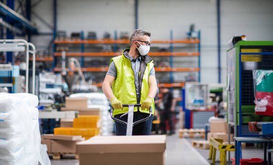 Porträt eines Arbeiters mit Schutzmaske, der in einer Fabrik oder einem Lagerhaus arbeitet. - HPIF15026