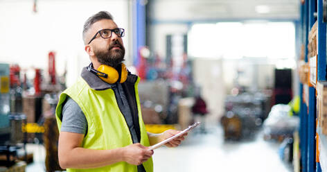 Techniker oder Ingenieur mit Schutzkopfhörern bei der Arbeit in einer Industriehalle. - HPIF15029