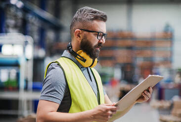 Techniker oder Ingenieur mit Schutzkopfhörern bei der Arbeit in einer Industriehalle. - HPIF15034