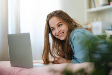 Beautiful happy young girl with laptop lying on bed and smiling, online dating and chatting concept. - HPIF15053