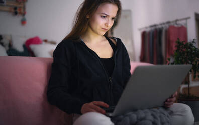 Worried young girl with laptop sitting indoors on floor, online dating and internet abuse concept. - HPIF15062