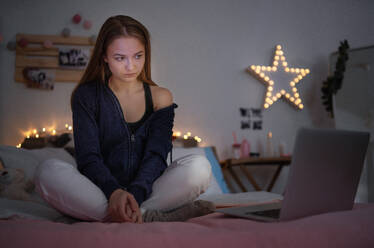 Besorgtes junges Mädchen mit Laptop sitzt drinnen auf dem Boden, Online-Dating und Internet-Missbrauch Konzept. - HPIF15067