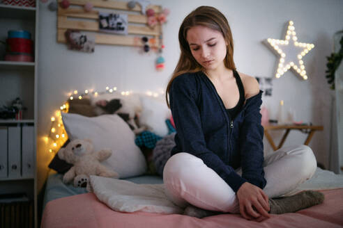 Besorgtes junges Mädchen sitzt drinnen auf dem Bett, Online-Dating und Internet-Missbrauch Konzept. - HPIF15068