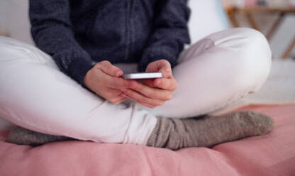 Midsection von unerkennbaren jungen Mädchen Smartphone sitzen drinnen, Internet-Missbrauch Konzept. - HPIF15069