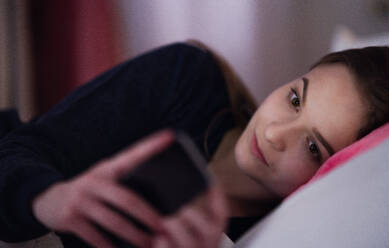 Ein junges Mädchen mit Smartphone auf dem Bett, Online-Dating-Konzept. - HPIF15076