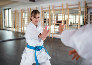 Zwei junge Frauen üben in einer Turnhalle Karate. - HPIF15095