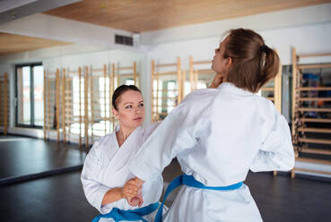 Zwei junge Frauen üben in einer Turnhalle Karate. - HPIF15099
