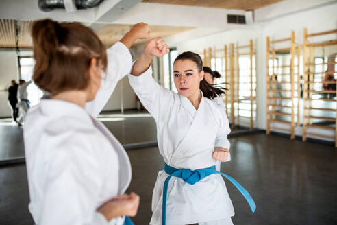 Zwei junge Frauen üben in einer Turnhalle Karate. - HPIF15100