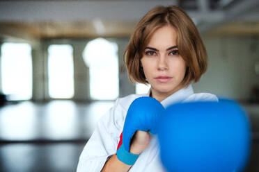 Eine attraktive junge Frau, die drinnen in einer Turnhalle Karate übt. - HPIF15110