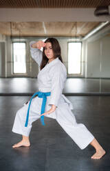 Eine attraktive junge Frau, die drinnen in einer Turnhalle Karate übt. - HPIF15113