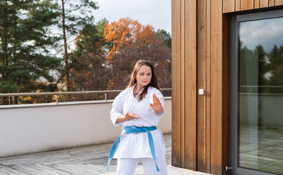 Eine attraktive junge Frau, die im Freien auf einer Terrasse Karate übt. - HPIF15117