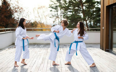 Eine Gruppe junger Frauen übt Karate im Freien auf einer Terrasse. - HPIF15122