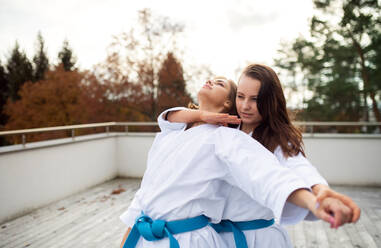 Zwei junge Frauen üben Karate im Freien auf einer Terrasse. - HPIF15124