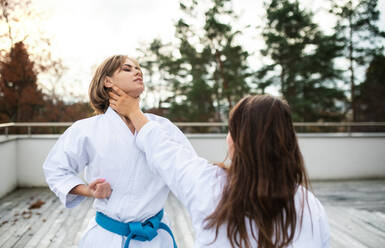 Zwei junge Frauen üben Karate im Freien auf einer Terrasse. - HPIF15125