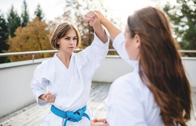 Zwei junge Frauen üben Karate im Freien auf einer Terrasse. - HPIF15126