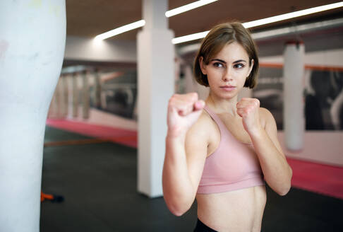 Vorderansicht einer jungen Frau, die in einer Turnhalle Karate übt. - HPIF15132
