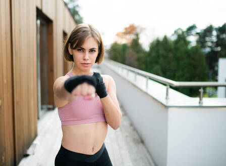Vorderansicht einer jungen Frau, die im Freien auf einer Terrasse Karate übt. - HPIF15135