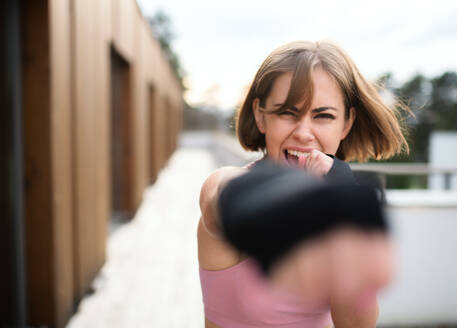 Vorderansicht einer jungen Frau, die im Freien auf einer Terrasse Karate übt. - HPIF15140