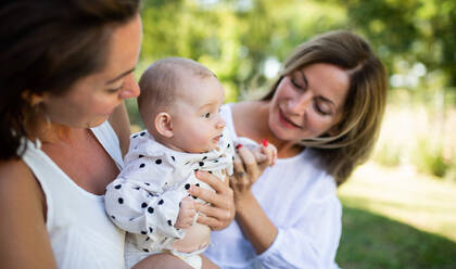 Woman with daughter and baby granddaughter resting outdoors in backyard, bonding. - HPIF15145