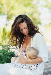 Portrait of woman nursing baby girl outdoors in backyard. - HPIF15160