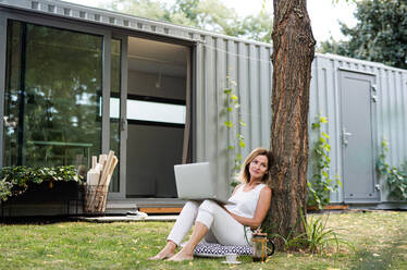 Mature woman working in home office outdoors in garden, using laptop computer. - HPIF15168