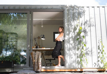 Side view of mature woman working in home office in container house in backyard, resting. - HPIF15191
