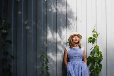 Porträt einer reifen Frau, die im Garten steht und sich mit geschlossenen Augen entspannt. Kopierraum. - HPIF15196