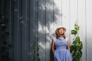 Portrait of mature woman standing outdoors in garden, relaxing with eyes closed. Copy space. - HPIF15196