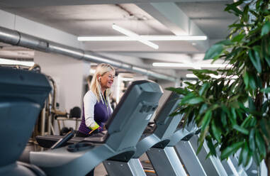 A side view of happy senior woman in gym doing cardio work out exercise. - HPIF15212