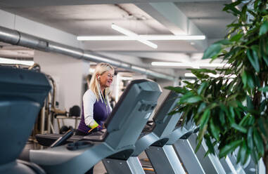 Eine Seitenansicht von glücklichen älteren Frau im Fitnessstudio tun Cardio-Work-out-Übung. - HPIF15212