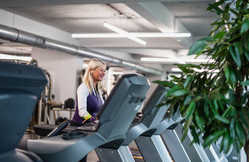 Eine Seitenansicht von glücklichen älteren Frau im Fitnessstudio tun Cardio-Work-out-Übung. - HPIF15212