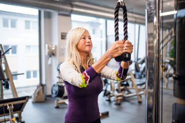 Ein Porträt einer attraktiven älteren Frau im Fitnessstudio, die Sport treibt. - HPIF15220