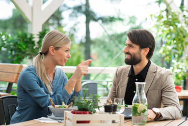 Ein glückliches Paar sitzt an einem Tisch im Freien auf einer Restaurantterrasse und unterhält sich. - HPIF15240