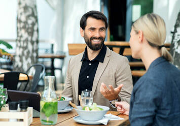 Ein glückliches Paar sitzt an einem Tisch im Freien auf einer Restaurantterrasse und unterhält sich. - HPIF15242