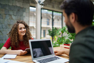 Young man and woman sitting and talking indoors in office, business meeting concept. - HPIF15266
