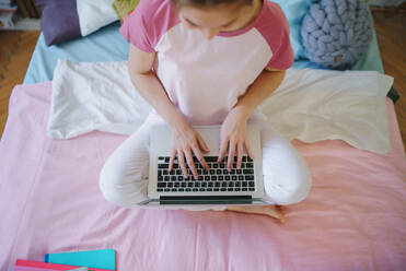 Top view of unrecognizable young girl with laptop on bed, working during quarantine. - HPIF15313