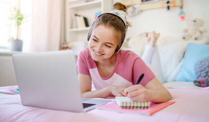 Junge Studentin mit Laptop auf dem Bett liegend, Online-Unterricht Konzept. - HPIF15314