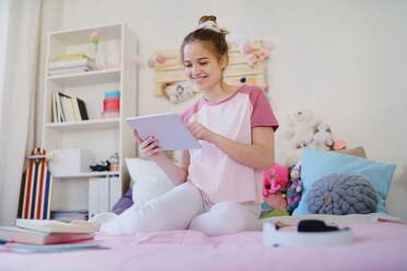 Junges Mädchen mit Tablet sitzen und entspannen auf dem Bett, Quarantäne-Konzept. - HPIF15317