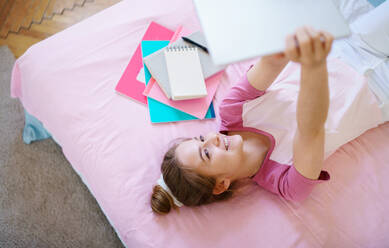 Young girl with tablet sitting and relaxing on bed, quarantine concept. - HPIF15320