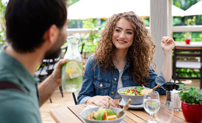 Ein glückliches Paar sitzt an einem Tisch im Freien auf einer Restaurantterrasse und unterhält sich. - HPIF15338