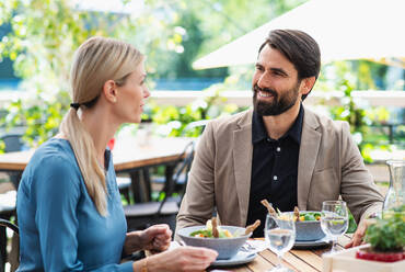 Ein glückliches Paar sitzt an einem Tisch im Freien auf einer Restaurantterrasse und unterhält sich. - HPIF15350