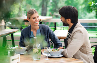 Ein glückliches Paar sitzt an einem Tisch im Freien auf einer Restaurantterrasse und unterhält sich. - HPIF15355