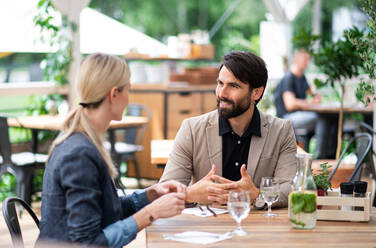 Ein glückliches Paar sitzt an einem Tisch im Freien auf einer Restaurantterrasse und unterhält sich. - HPIF15356