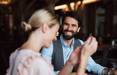 A happy couple sitting indoors in restaurant, talking. - HPIF15368